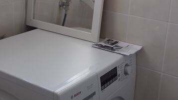 Une machine à laver Bosch blanche et compacte, à chargement frontal, dotée d’un panneau de commande et d’un miroir placé au-dessus.