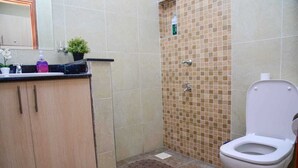 A bathroom with a toilet, sink, and shower. - Sherry Homes West suites (Nairobi)