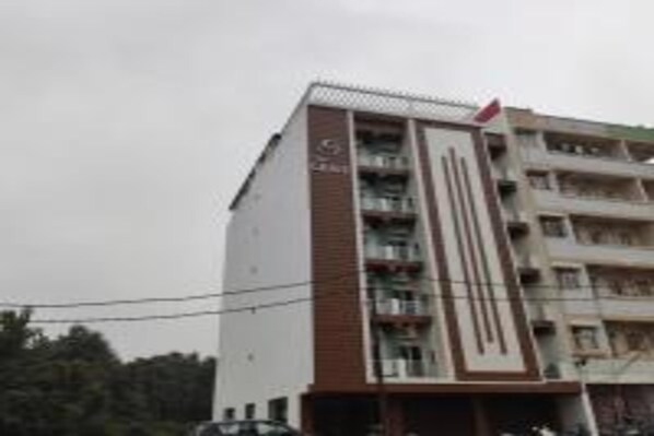 A multi-story hotel with a prominent vertical design element on the facade. - Hotel The Grace (Rishikesh)