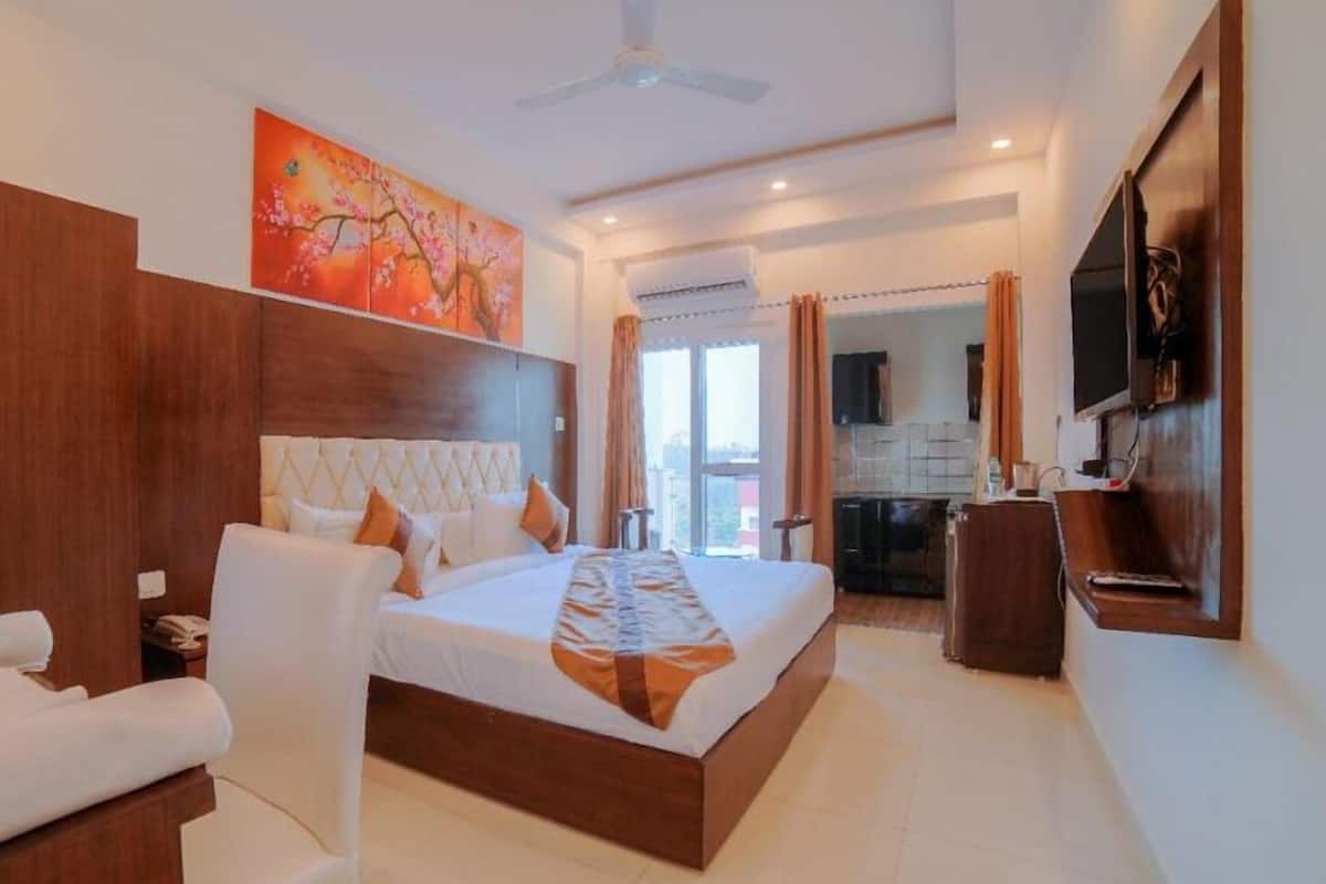 A modern hotel room with a large bed, a wardrobe, a TV, and a balcony with curtains.