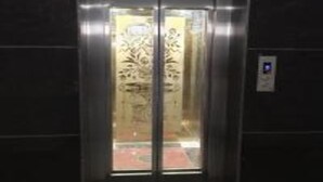 An elevator with a glass door and a reflective interior. - Hotel The Grace (Rishikesh)