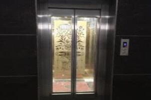 Un ascenseur doté d’une porte en verre et d’un intérieur réfléchissant.