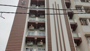 A multi-story building with a modern design, featuring balconies with air conditioning units, a prominent vertical wooden panel, and a sign reading "The Grace". - Hotel The Grace (Rishikesh)