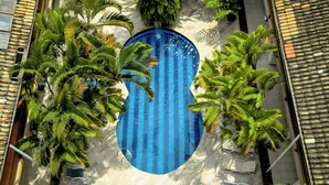An aerial view of a swimming pool surrounded by palm trees and lounge chairs. - Hotel Dellamares (Ubatuba)