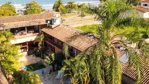 A coastal property with a swimming pool, outdoor seating, and a view of the sea and hills. - Hotel Dellamares (Ubatuba)