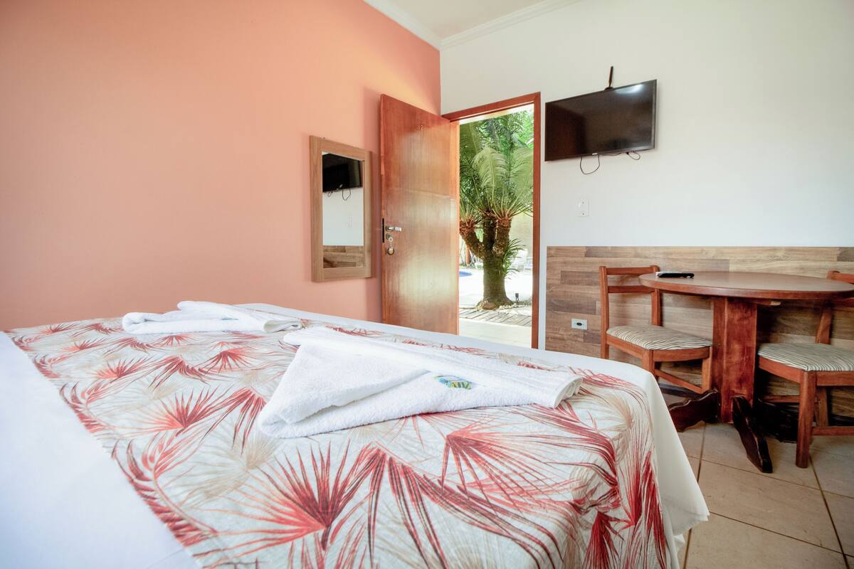 A hotel room with a bed, a wooden table, and a TV.