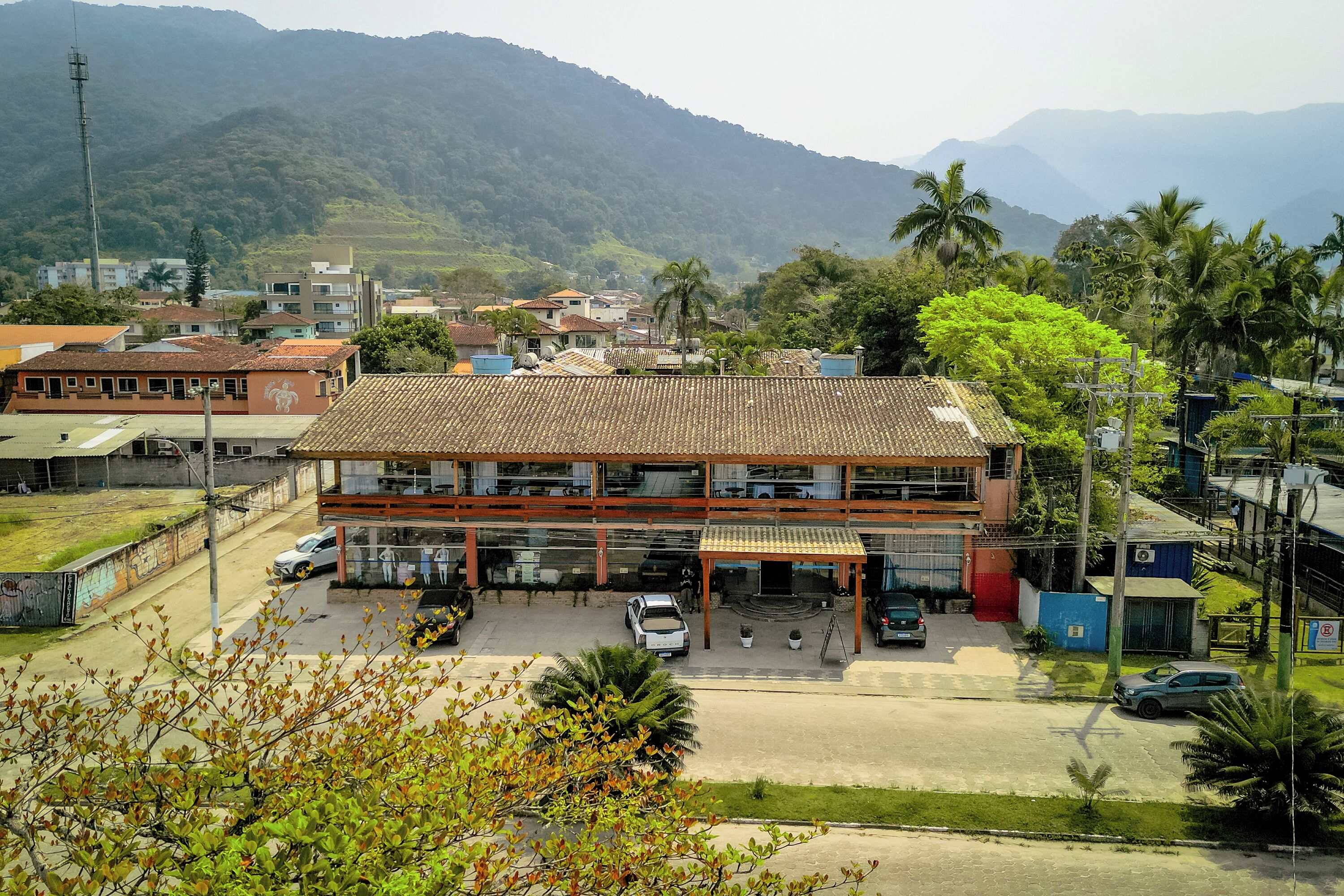 A building with a tiled roof, a covered parking area, and a view of surrounding buildings and mountains.