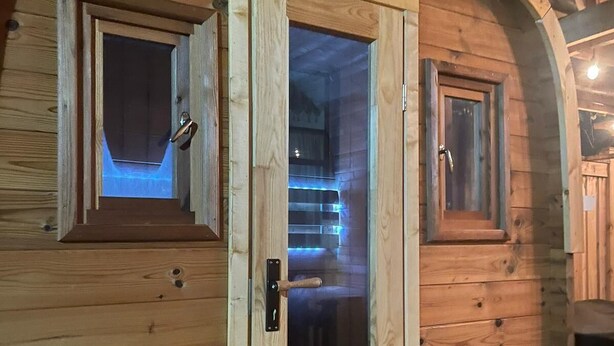 Une cabane en bois dotée d’une grande porte centrale et de deux petites fenêtres de chaque côté.