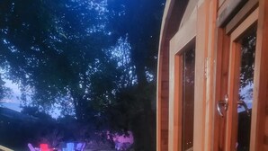 Une terrasse en bois avec une rambarde, un chemin en pierre et des sièges d’extérieur illuminés par des néons.
