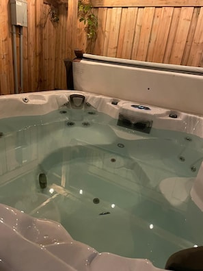 A hot tub with a wooden wall background and a visible electrical box.
