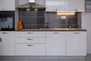 Apartamento | Cozinha privada | Geladeira, cooktop, talheres/pratos/utensílios de cozinha