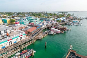 Une ville côtière dotée d’une jetée imposante, de différents bâtiments, dont un hôtel, et de bateaux amarrés dans le port de plaisance.