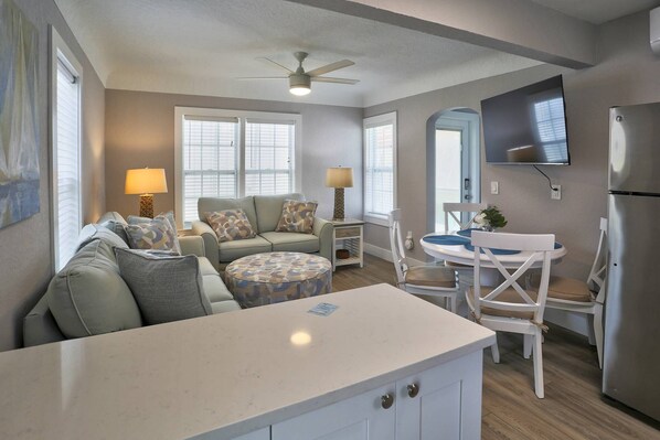 A compact living space with a kitchenette, a dining area, and a seating area with a sofa and chairs.