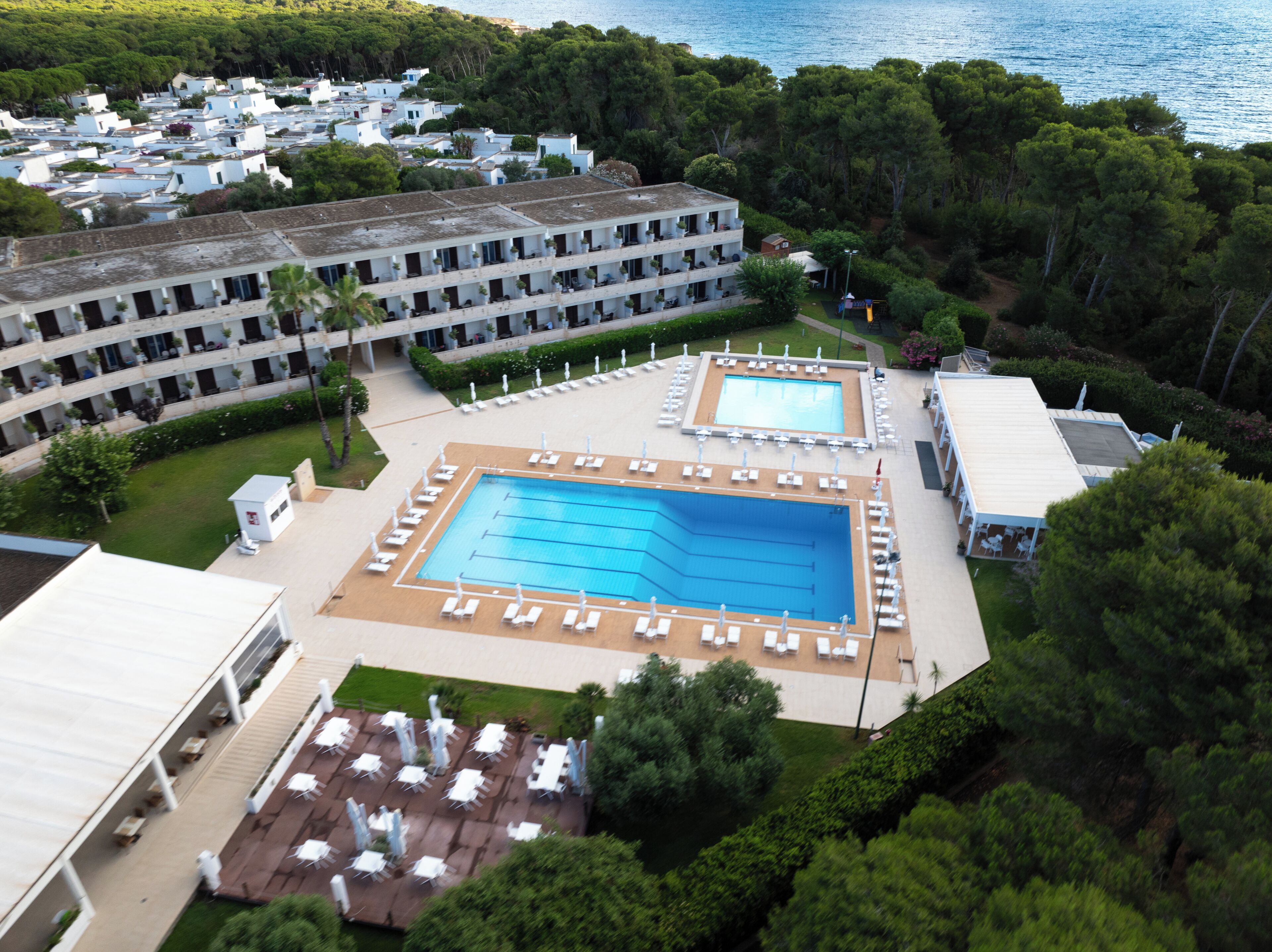 A resort with multiple swimming pools, a large building with balconies, and a lush green landscape.