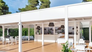 Un espace extérieur abrité, doté de mobilier blanc et de lampes suspendues.