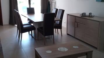 Ein moderner Essbereich mit Tisch, Stühlen, einem kleinen Schrank und einem Fenster mit Vorhängen.
