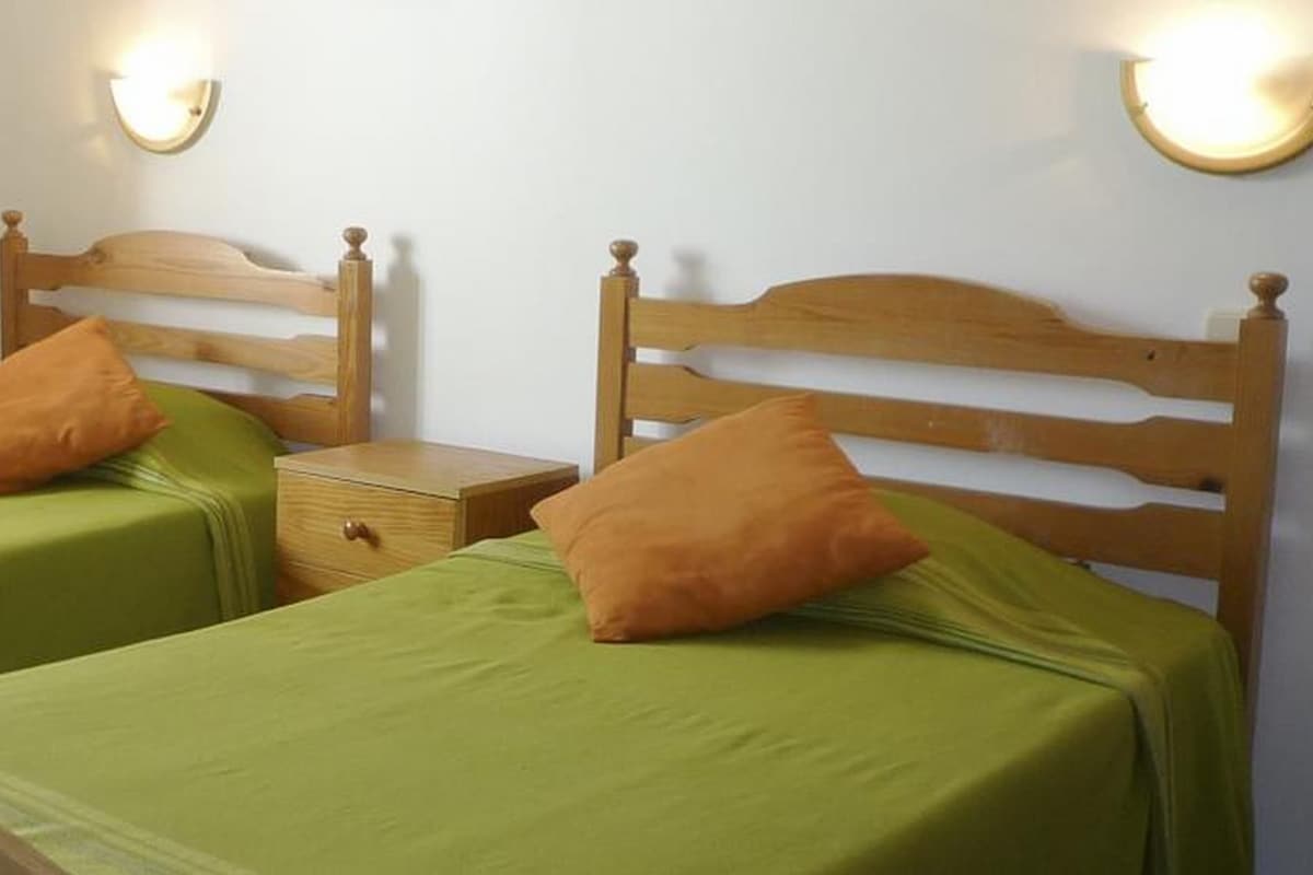 Dos camas individuales con cabeceros de madera, ropa de cama verde y almohadas a juego.