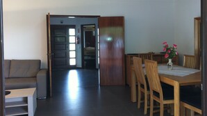 Un comedor con una mesa y sillas de madera, un sofá y una mesita con un jarrón de flores.
