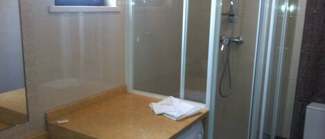 A bathroom with a glass-enclosed shower, a sink, and a washing machine.