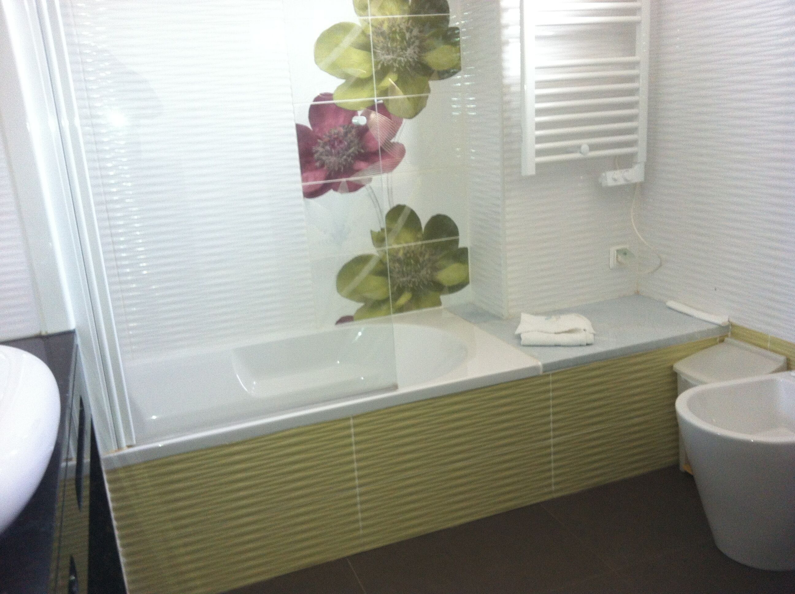 Ein Badezimmer mit Duschkabine aus Glas, einem weißen Waschbecken und einer Toilette.
