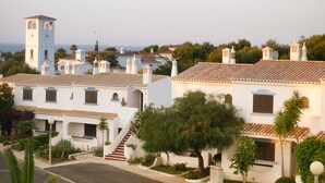 Un pueblo costero con edificios blancos, una torre del reloj y una vista despejada del mar.