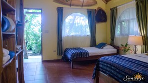 Una habitación con dos camas, techo de madera, un ventanal con cortinas y una puerta que da al exterior.