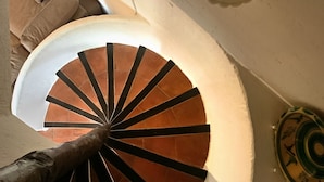 En spiraltrappe med en hvid væg og en dekorativ tallerken til højre.