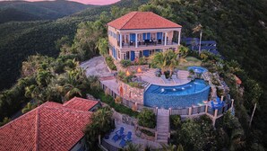A two-story house with a swimming pool, surrounded by lush greenery and hills. - Sol Inclination~ 4b/4.5b HUGE views, updated in and out, backup power! (St.John)