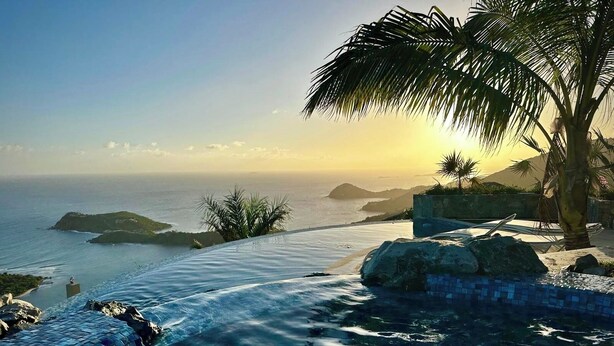 A pool with clear blue water, a palm tree, and a view of the ocean and islands. - Sol Inclination~ 4b/4.5b HUGE views, updated in and out, backup power! (St.John)