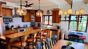 A spacious kitchen with wooden cabinets, a central island with bar stools, and pendant lighting. - Sol Inclination~ 4b/4.5b HUGE views, updated in and out, backup power! (St.John)