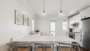 Una cocina moderna con una isla grande, electrodomésticos de acero inoxidable y un comedor con tres sillas.