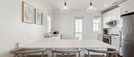 A modern kitchen with a large island, stainless steel appliances, and a dining area with three chairs.