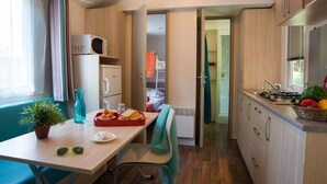 Une cuisine compacte comprenant un coin repas, un four à micro-ondes, un réfrigérateur et un évier.