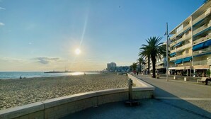 Une promenade en bord de mer, avec un mur de pierre, des palmiers et un bâtiment doté de balcons.