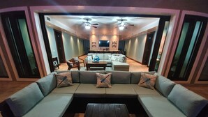 A modern living room with a sectional sofa, a wooden coffee table, and a dining area in the background.