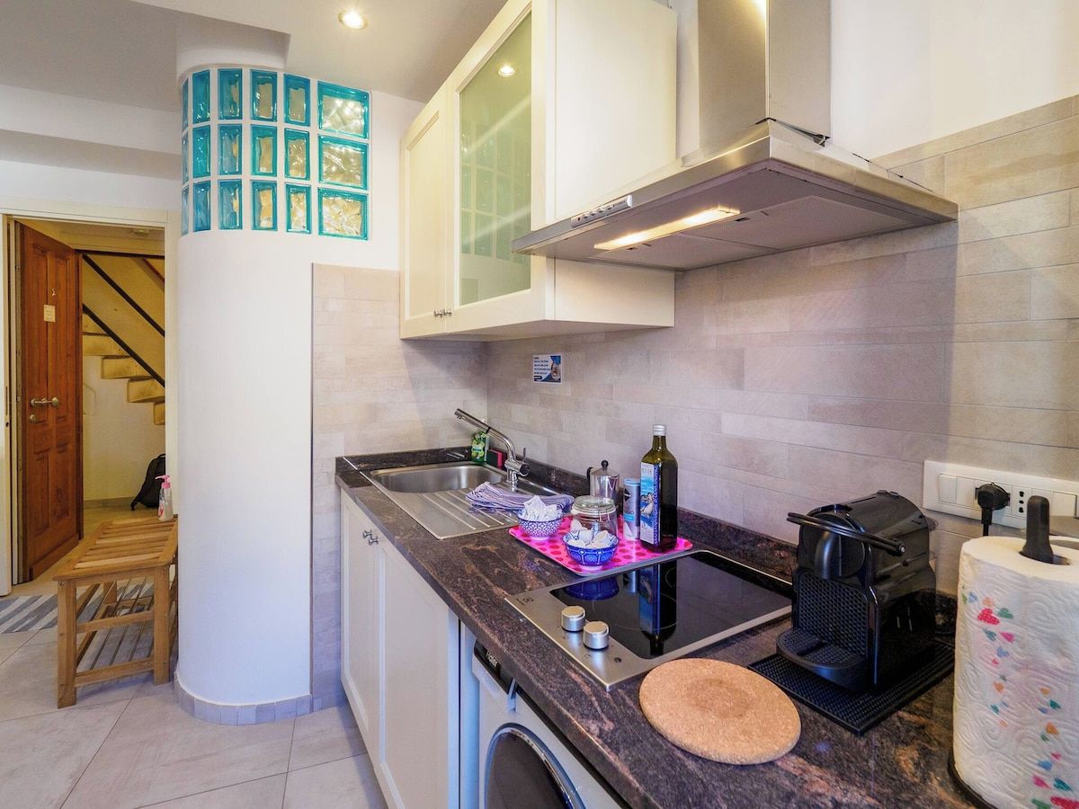 A compact kitchen with a built-in oven, a coffee machine, and a washing machine.