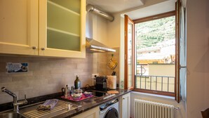 Une cuisine équipée d’un lave-linge, une fenêtre donnant sur une colline et un panneau accroché au mur.