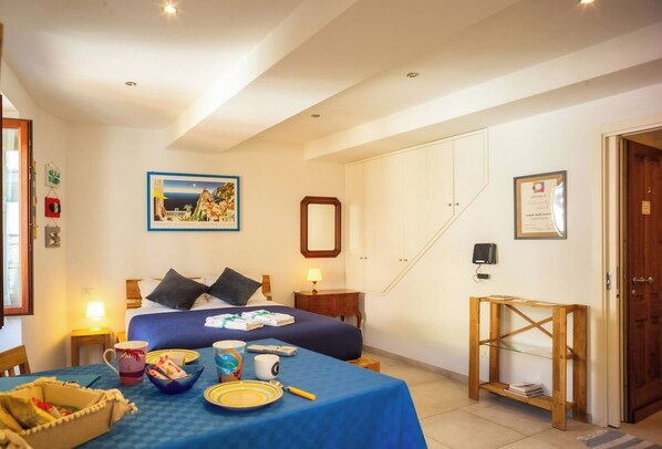 A hotel room with a bed, bedside table, lamp, and a framed picture on the wall.
