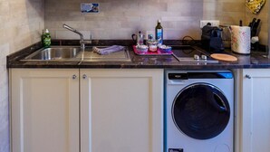 Une cuisine équipée d’un lave-linge et d’un sèche-linge intégrés, d’un évier et de divers ustensiles de cuisine disposés sur le plan de travail.