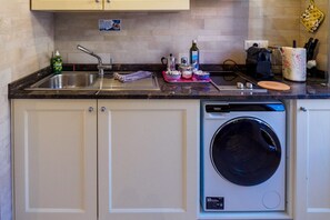 Una cocina con lavadora y secadora integradas, un lavamanos y varios objetos de cocina sobre la encimera.