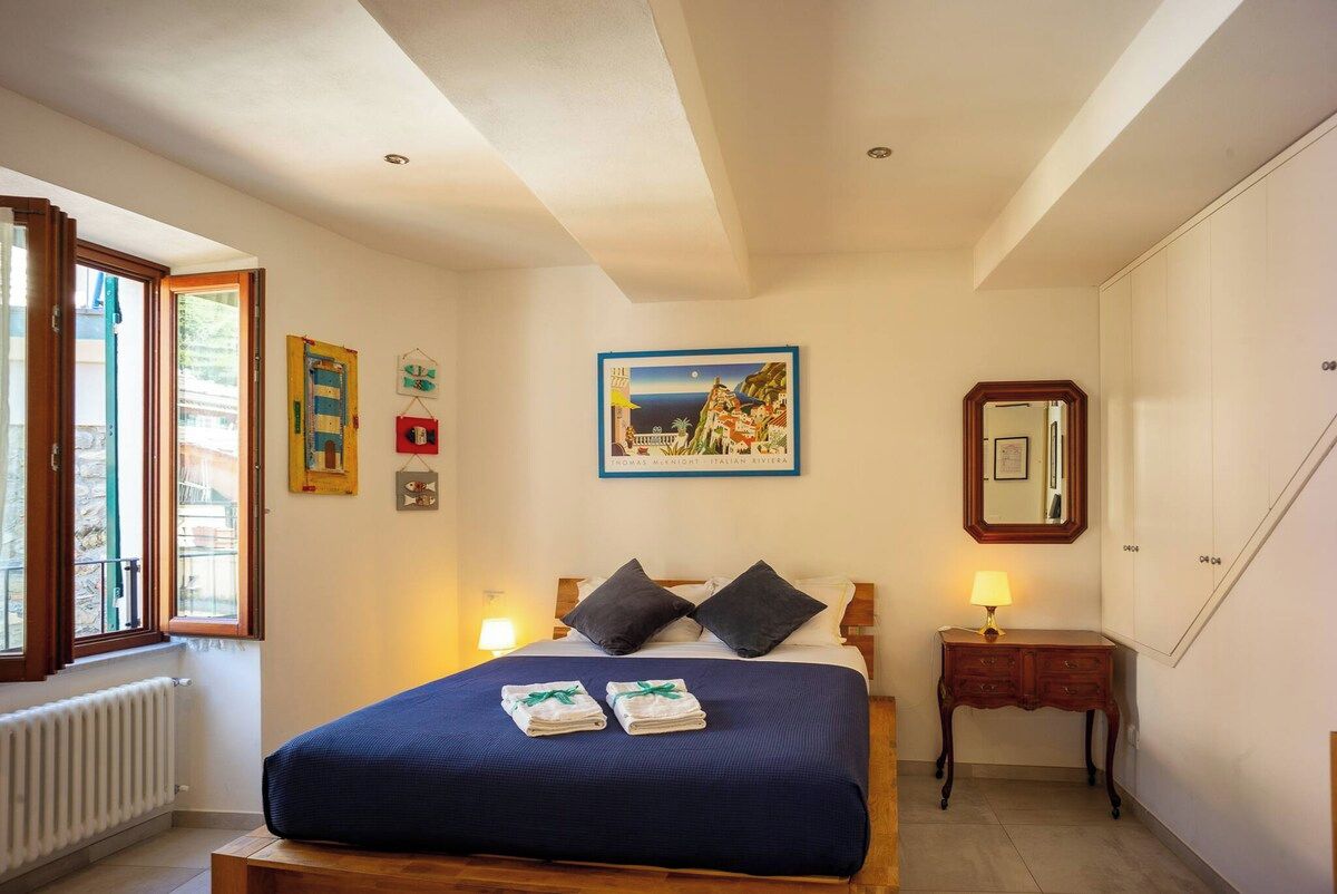 Una camera da letto con un letto, un comodino, una lampada e un quadro appeso al muro.