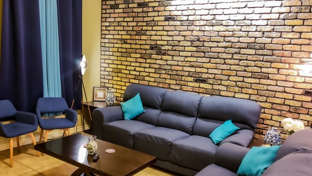 A living room with a brick wall, dark-colored sofa, two armchairs, a coffee table, and a lamp. - Chicago Style Town home in a gated community!!Spacious 1100sqft (Edinburg)