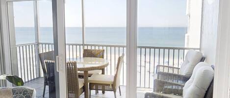 A balcony with a table and chairs, a wicker sofa, and a view of the sea.