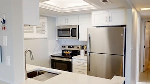 A modern kitchen with stainless steel appliances, white cabinetry, and a built-in oven. - Siesta Key Beach Front Condo! Breathtaking view! (Siesta Key)