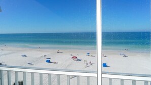 A beach view from a window with a clear sky, sandy beach, and a few umbrellas and beach chairs. - Siesta Key Beach Front Condo! Breathtaking view! (Siesta Key)