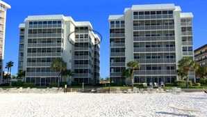 A beachfront hotel with multiple floors, balconies, and a sandy beach area with sun loungers. - Siesta Key Beach Front Condo! Breathtaking view! (Siesta Key)