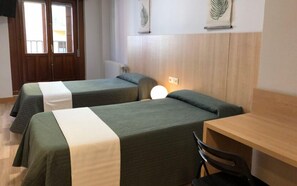 Una habitación de hotel con dos camas individuales, un escritorio de madera y una silla.