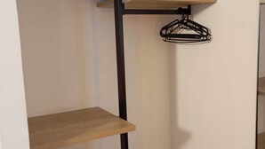 A multi-tiered wooden shelving unit with a black metal frame, holding folded towels and a black hanger. - Hostal Bearan (Pamplona)
