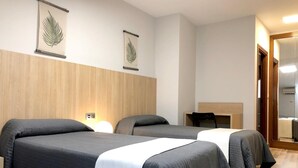 A hotel room with three beds, wooden paneling on the walls, and two wall-mounted leaf decorations. - Hostal Bearan (Pamplona)