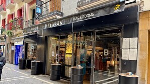 A storefront with 'BEARÁN BAR & ROOMS' signage, large black barrels outside, and a visible menu board. - Hostal Bearan (Pamplona)